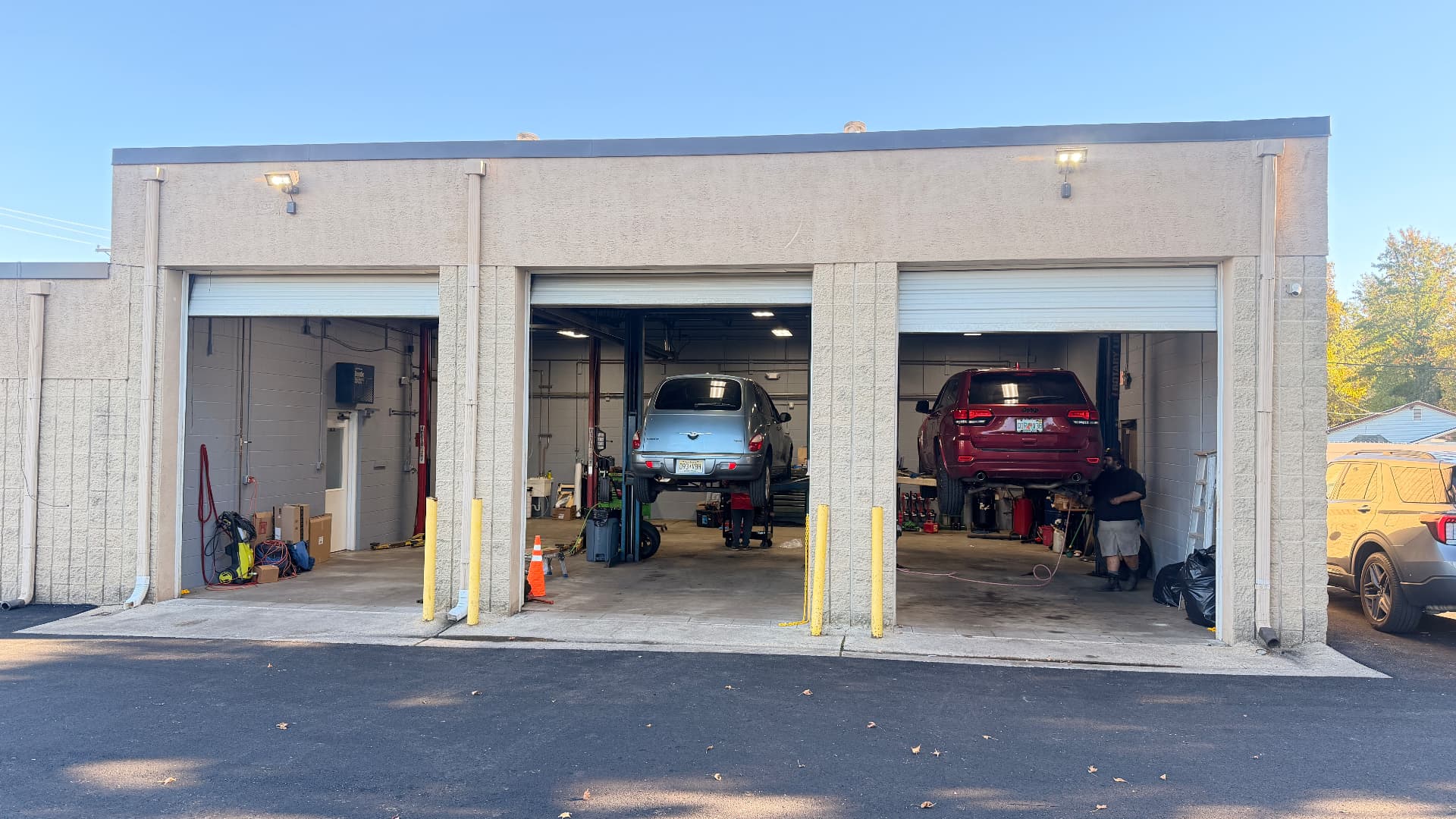 The shop's three bays with a PT Cruiser and a Jeep Grand Cherokee up on the lifts